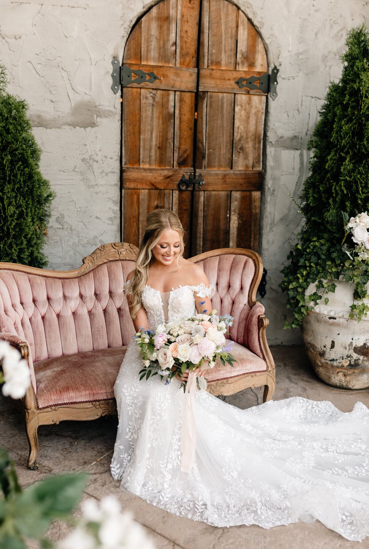 Bride in a lace wedding gown seated with her bouquet